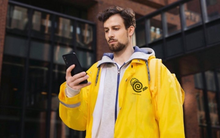 Курьер смотрит маршрут в приложении на смартфоне